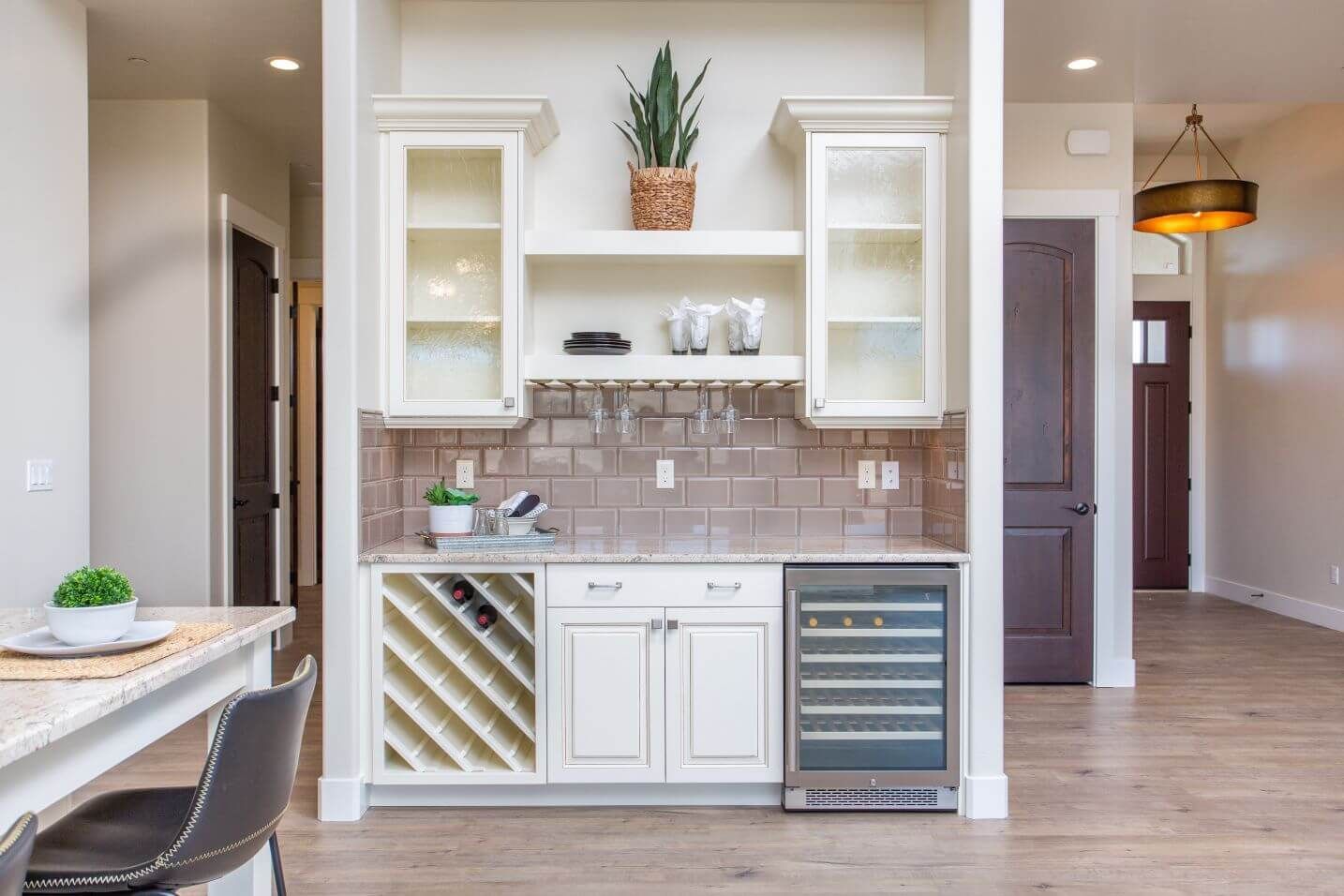 A kitchen with white cabinets , a wine cooler and a wine rack.