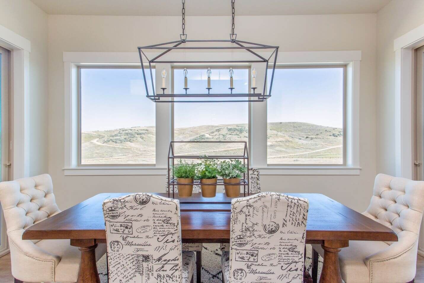 A dining room with a wooden table and chairs and a large window.