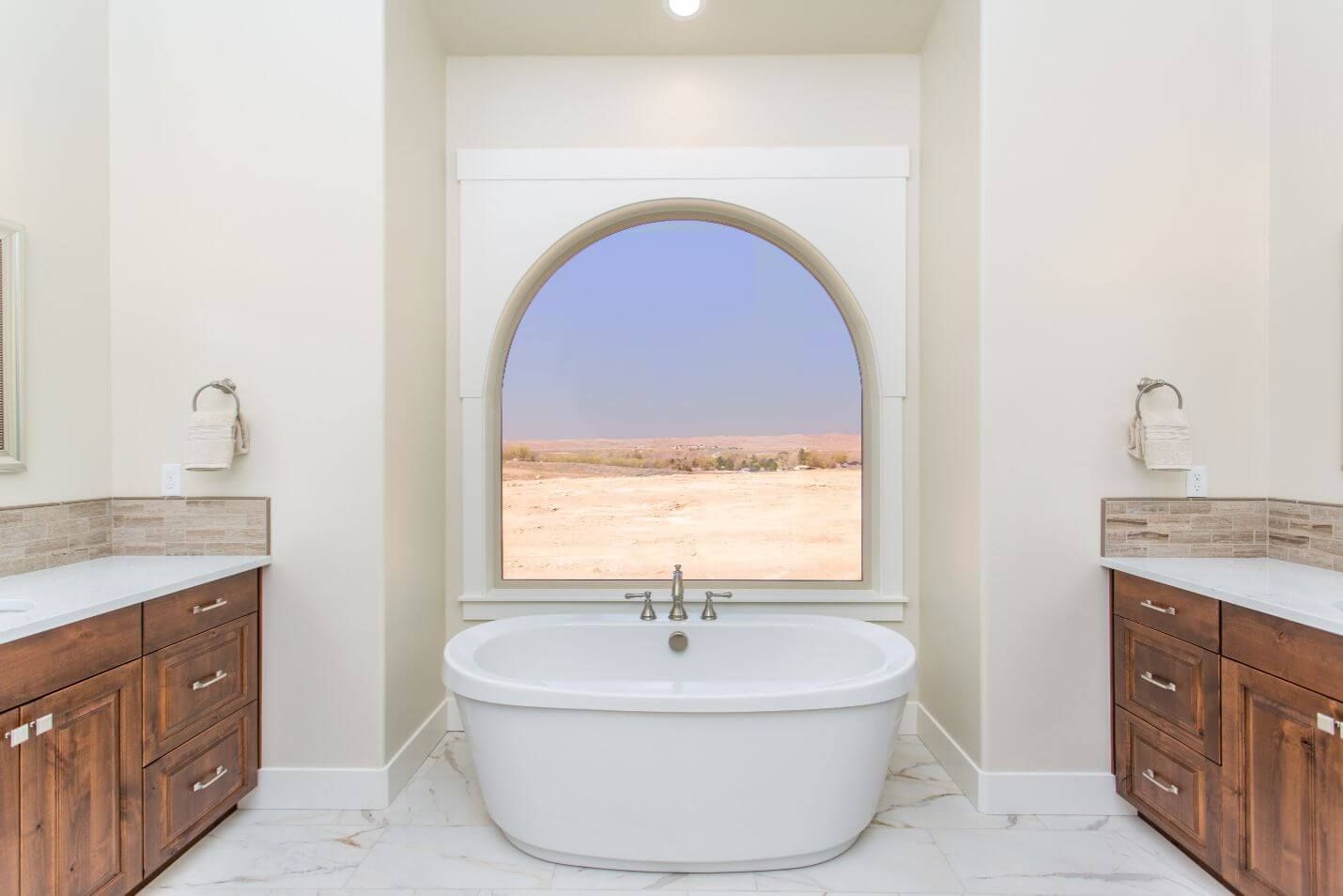 A bathroom with two sinks , a tub and a window.