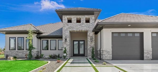 A large house with a stone wall in front of it.
