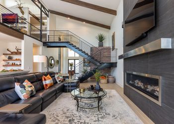 A living room with a couch , fireplace , television and stairs.