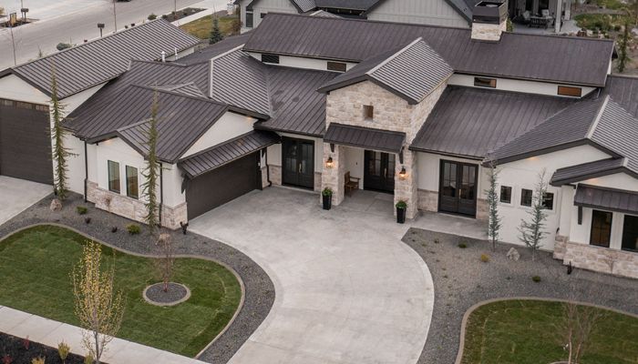 A large white house with a porch and a lot of windows is sitting on top of a dirt field.