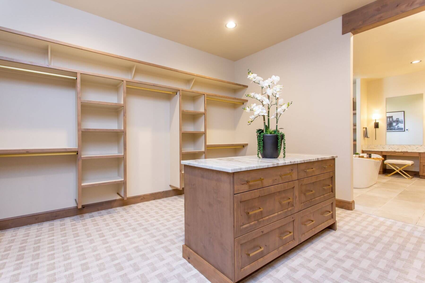 Spacious walk-in closet with built-in shelves and drawers. A central island with an orchid plant.