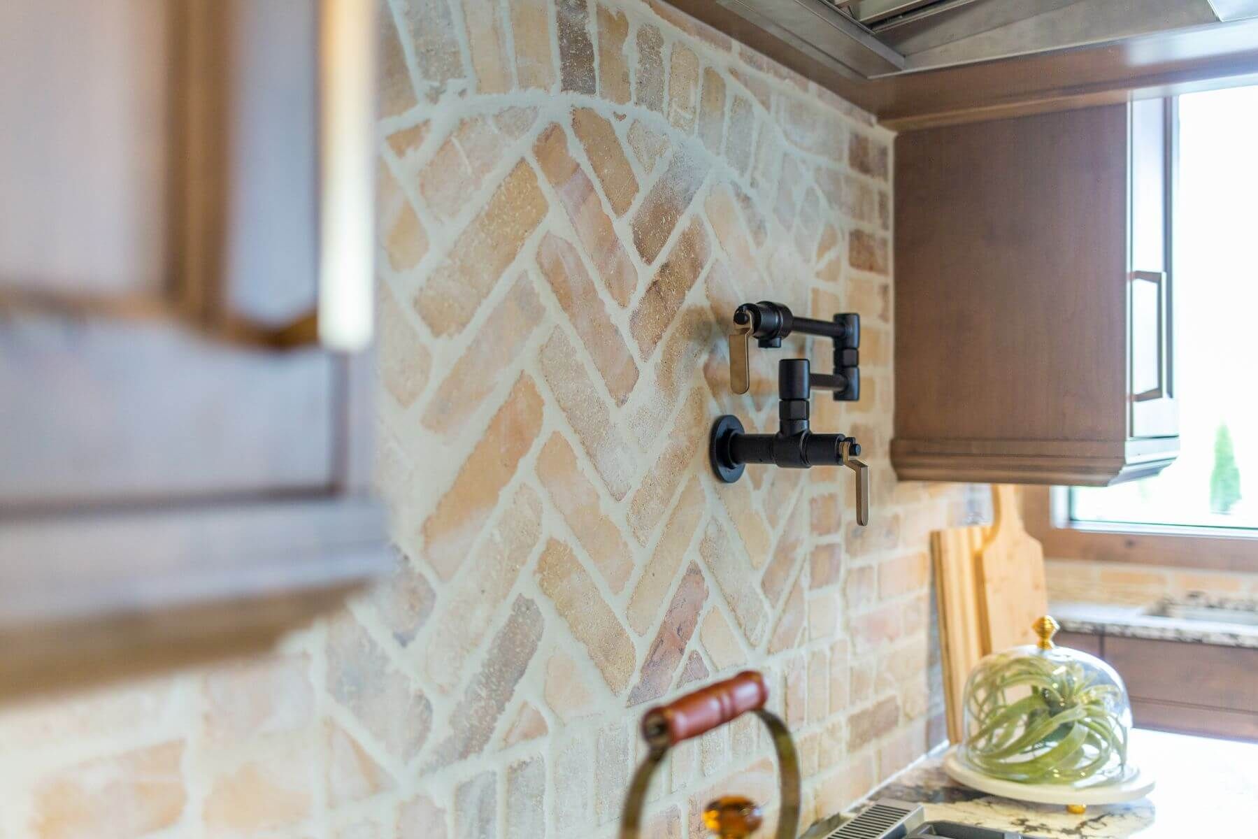 Herringbone brick backsplash in kitchen with a mounted TV bracket.