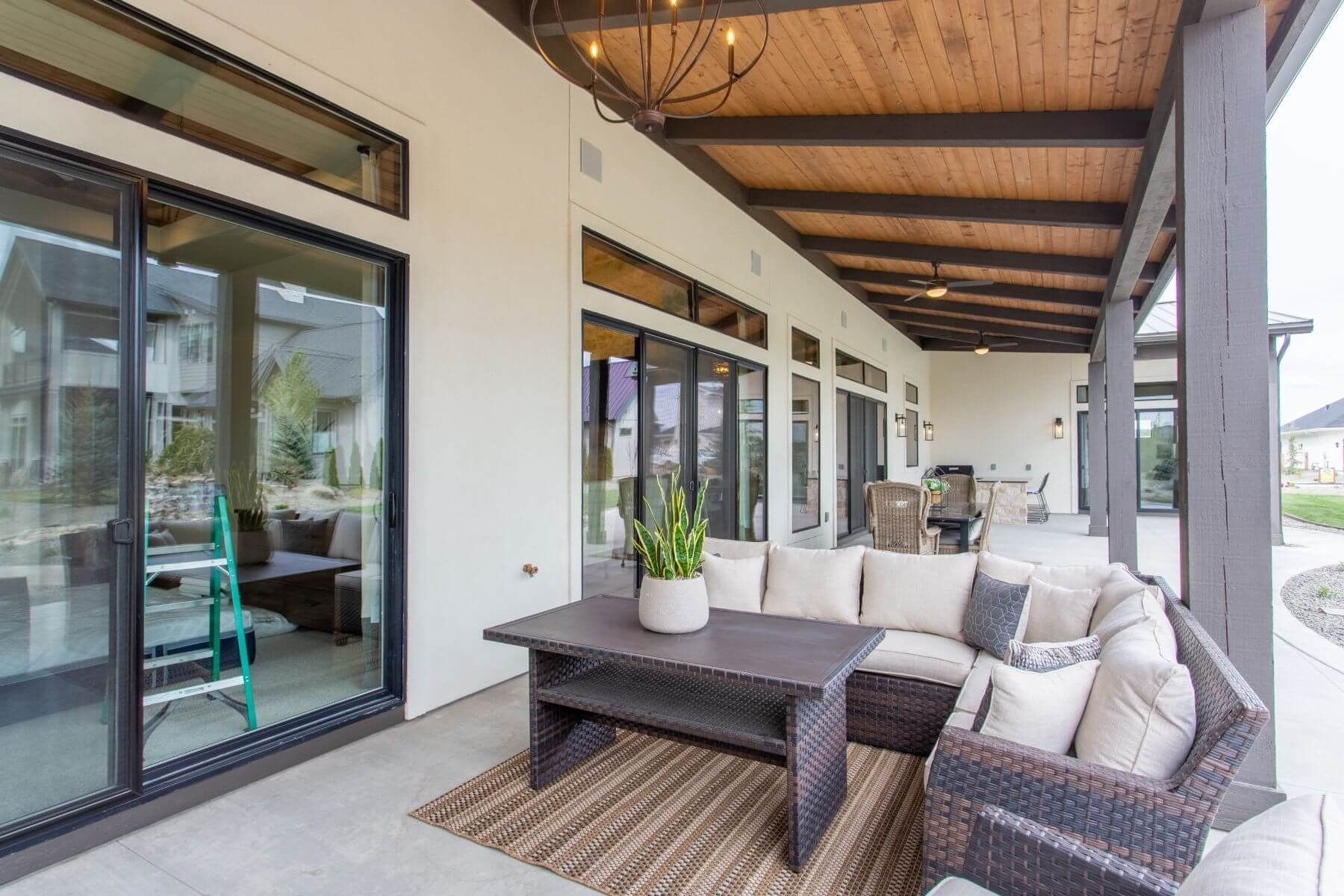 Patio with sectional sofa, rug, and sliding glass doors. Wooden ceiling with light fixture.