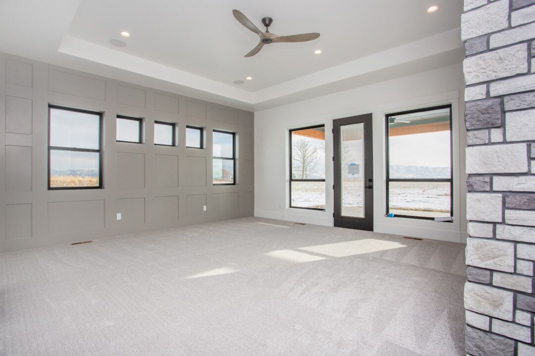 An empty living room with a ceiling fan and a brick wall.