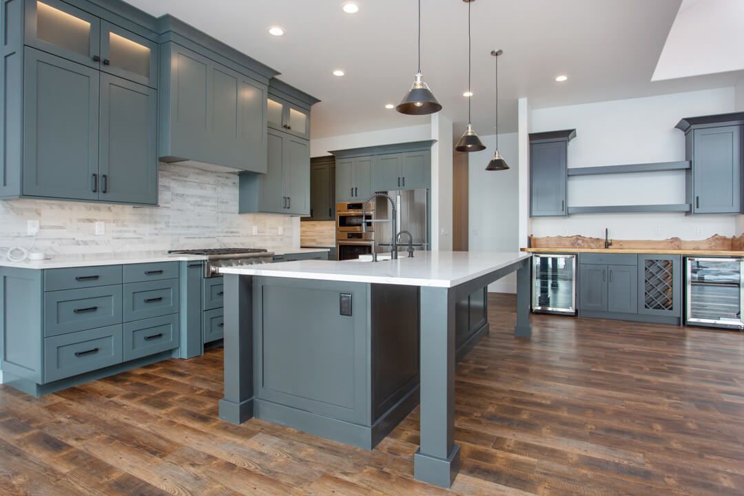 A kitchen with gray cabinets and a large island in the middle
