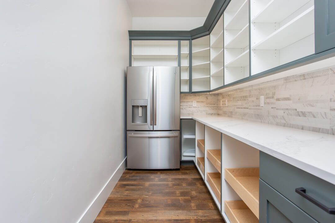 A pantry with a refrigerator and shelves in a kitchen.