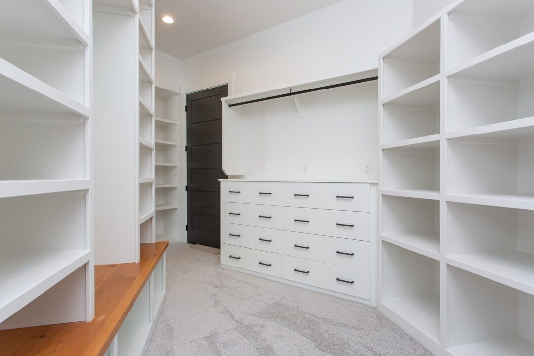 A walk in closet with lots of shelves and drawers.