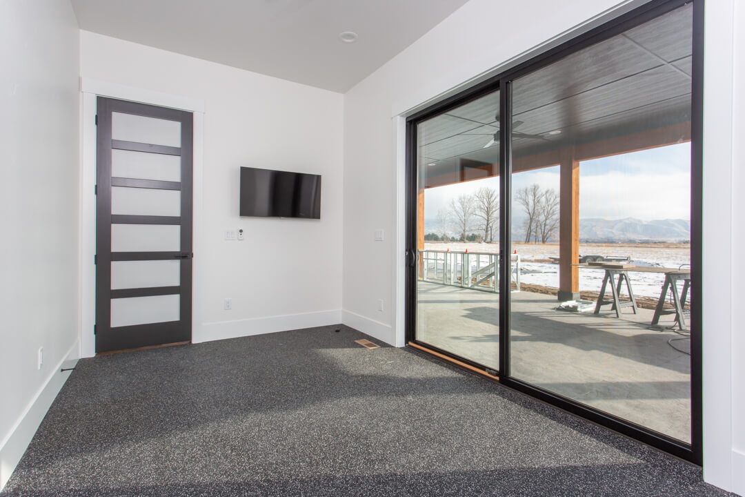 An empty room with sliding glass doors and a flat screen tv.