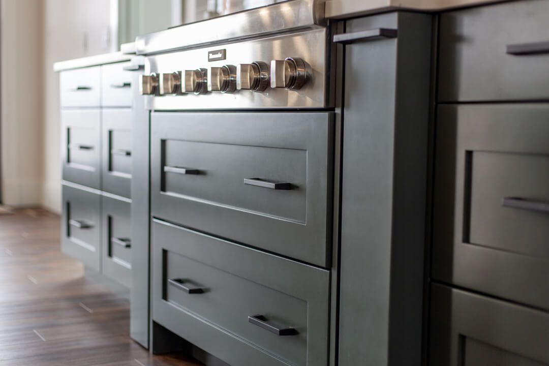 A kitchen with stainless steel appliances and gray cabinets.