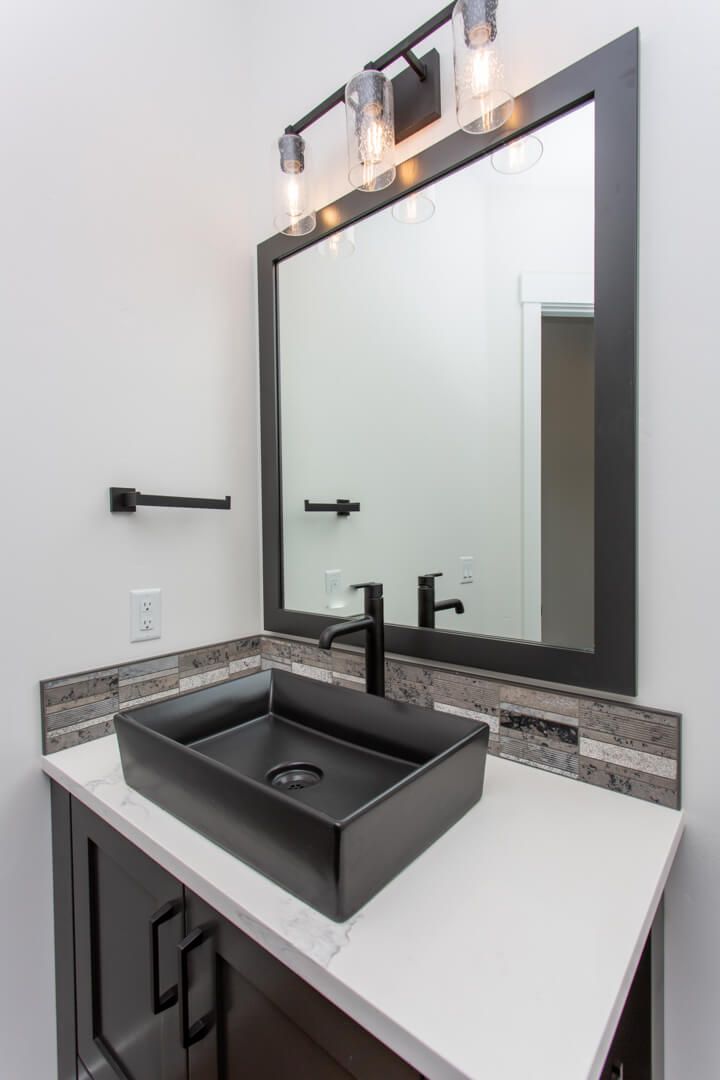 A bathroom with a black sink and a large mirror.