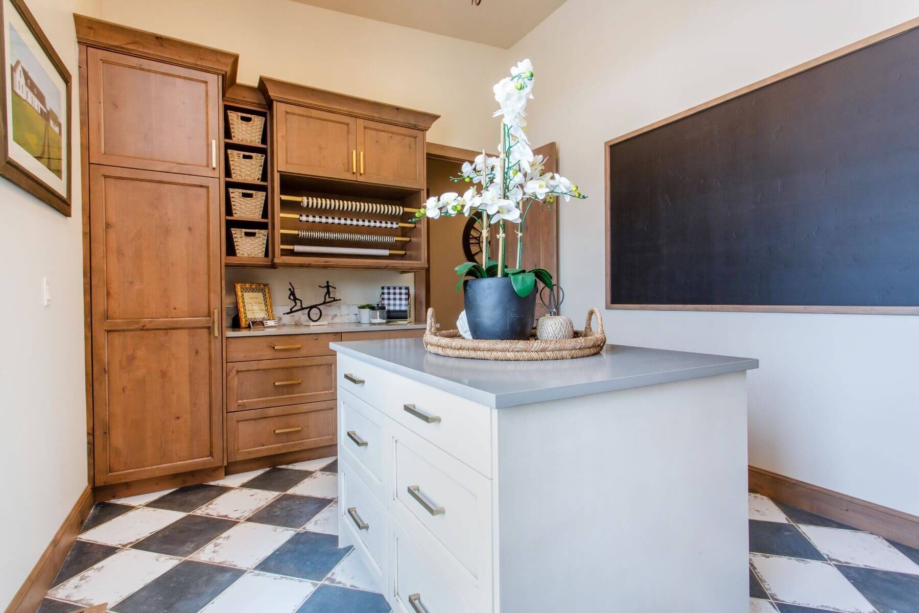 Craft room with cabinetry, island, chalkboard, and checkered floor.