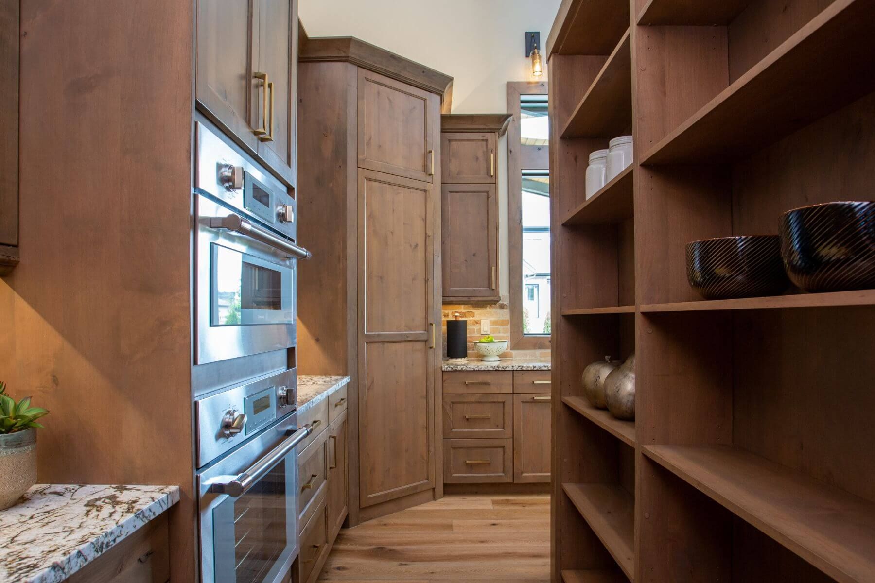 Kitchen with built-in oven, pantry, and light brown wood cabinetry.