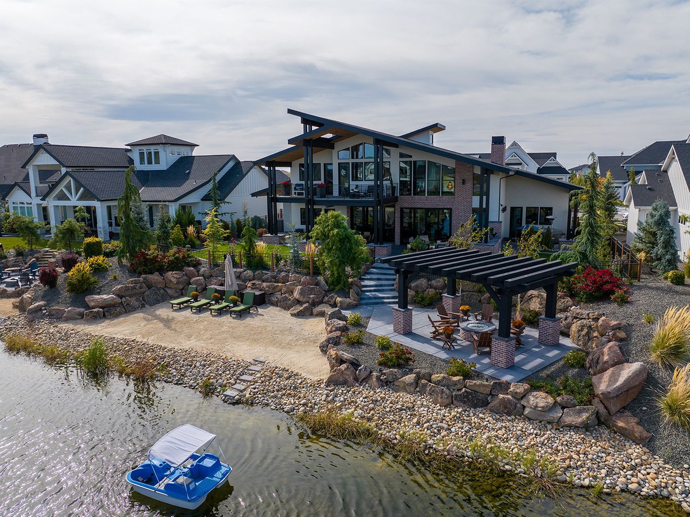 An aerial view of a large house next to a lake with a boat in the water.