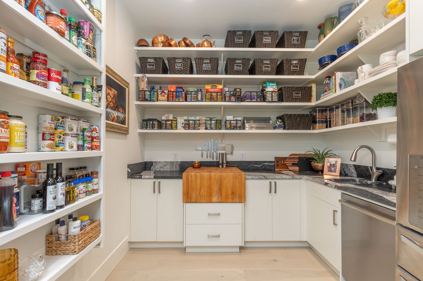 A kitchen with a pantry filled with lots of food and a sink.