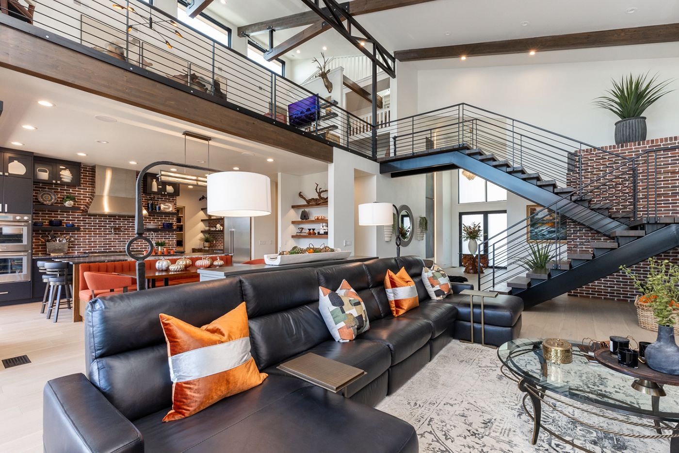 A living room with a large black couch and stairs leading up to the second floor.