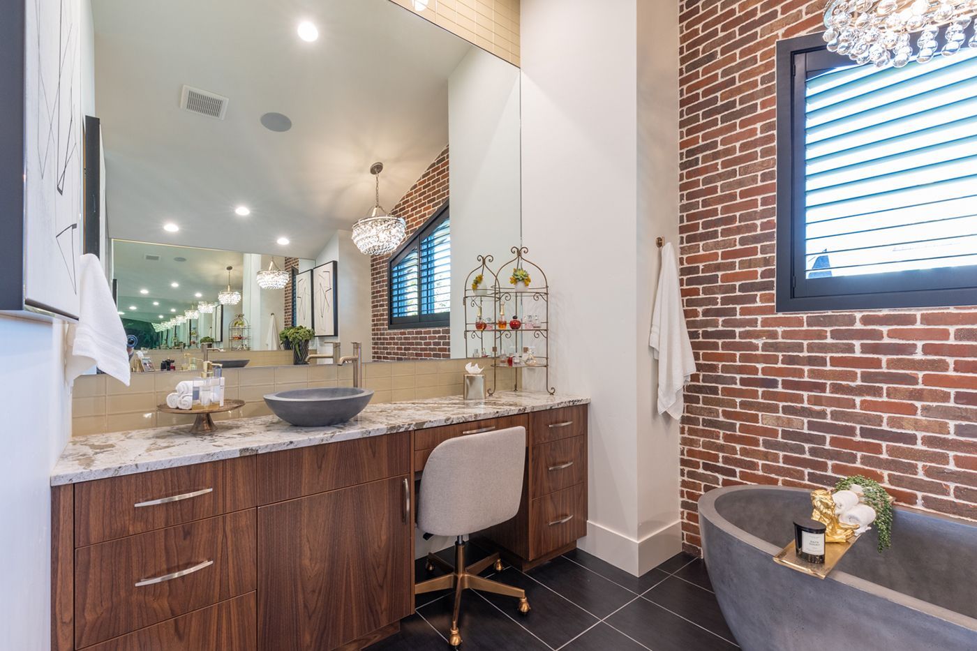 A bathroom with a tub , sink , mirror and brick wall.