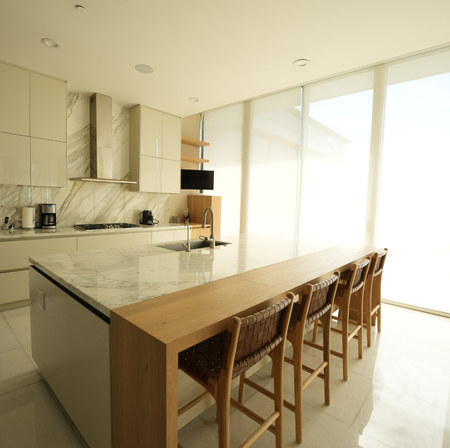 A kitchen with a marble counter top and wooden chairs