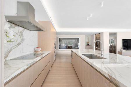 A kitchen with marble counter tops , wooden cabinets , stainless steel appliances and a large island.