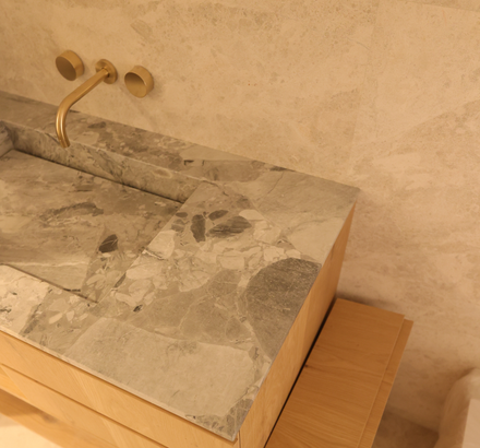 A bathroom sink with a marble counter top and a brass faucet