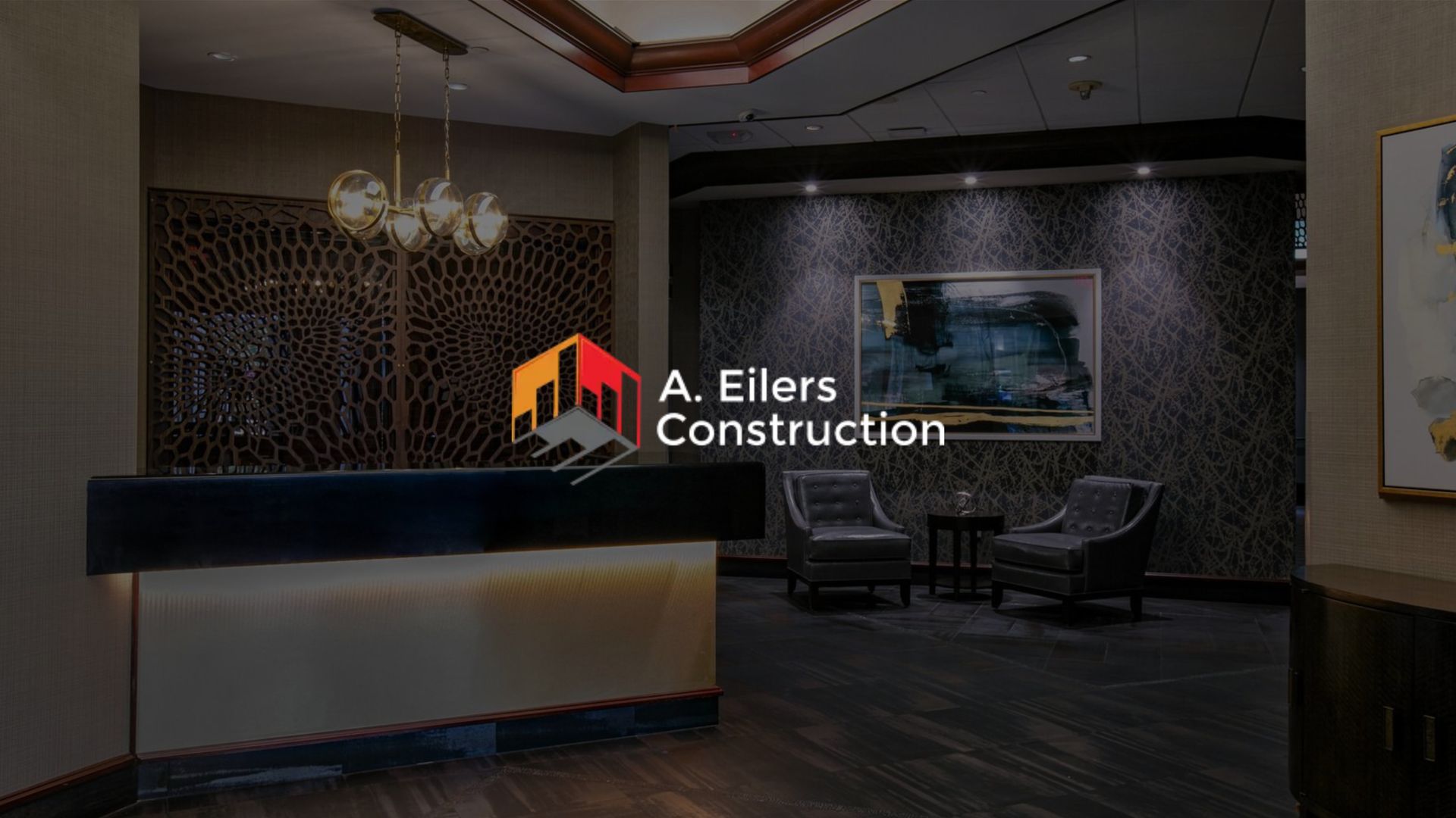 A. Eilers Construction logo over a modern, dimly lit office lobby with reception desk and seating