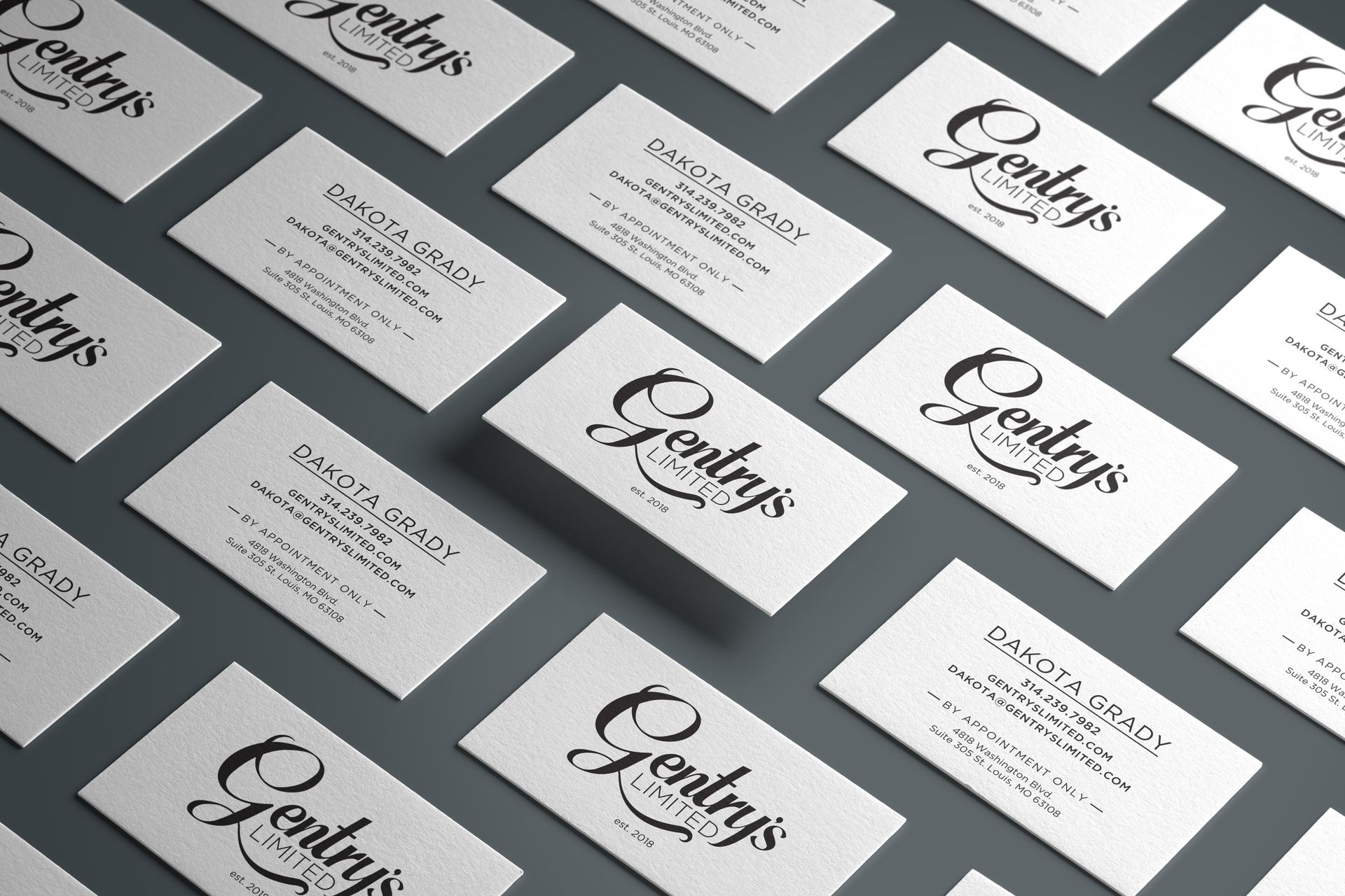 Business cards with cursive logo text arranged diagonally on a gray surface
