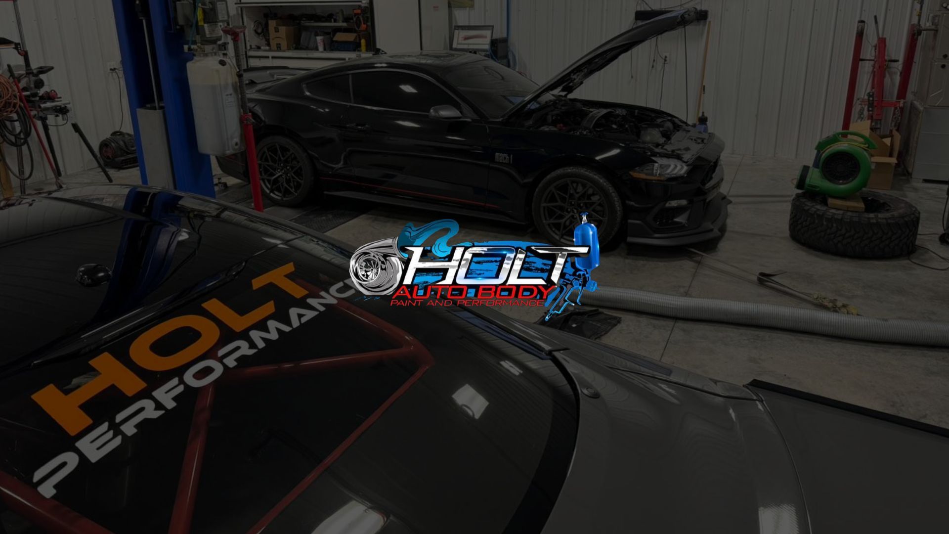 Auto shop interior with black sports car and HOLT Performance logo on a hood in the foreground