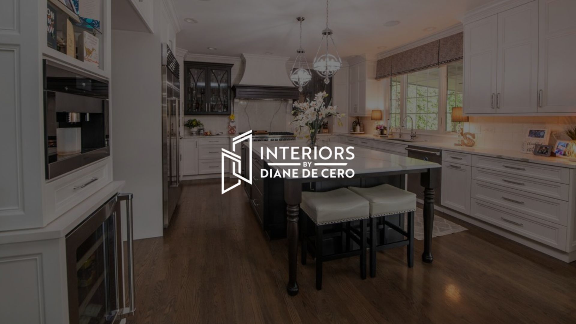 Modern white kitchen with dark wood island, pendant lights, and stainless appliances