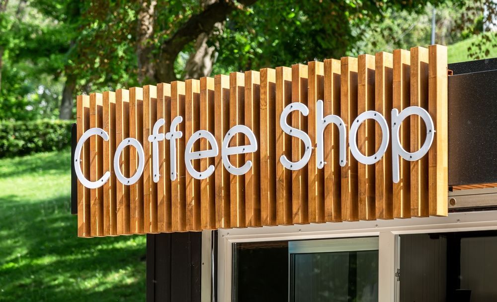 A coffee shop with a wooden sign on the side of it — Sign Media Solutions in Ballina, NSW