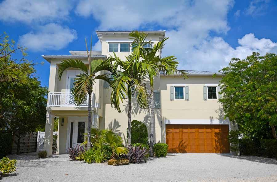 A large house with a garage and palm trees in front of it