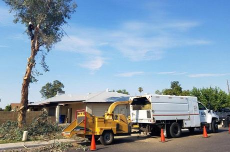 A tree chipper is parked on the side of the road next to a house.