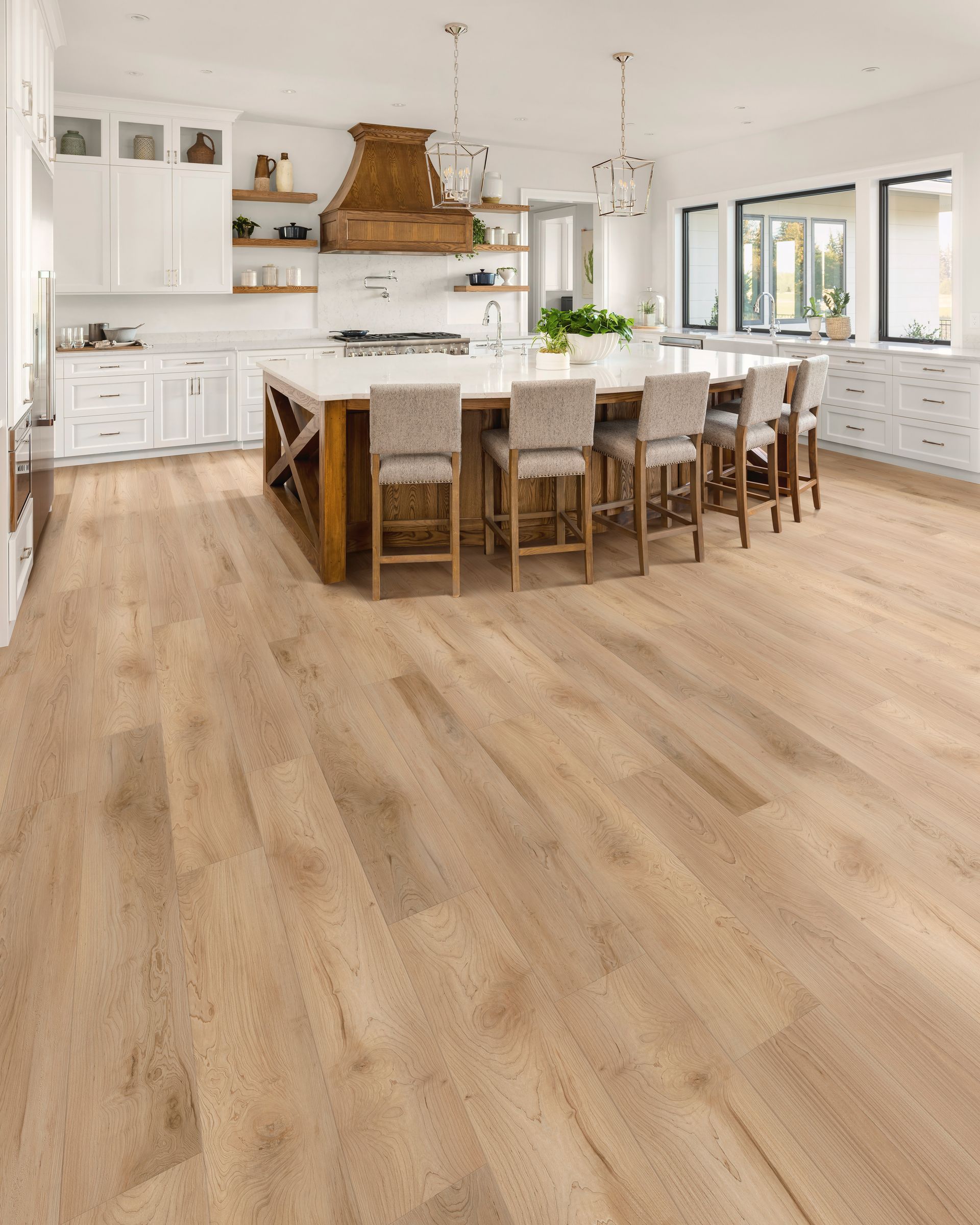 Bright modern kitchen with a large island, white cabinets, wood accents, and light wood flooring