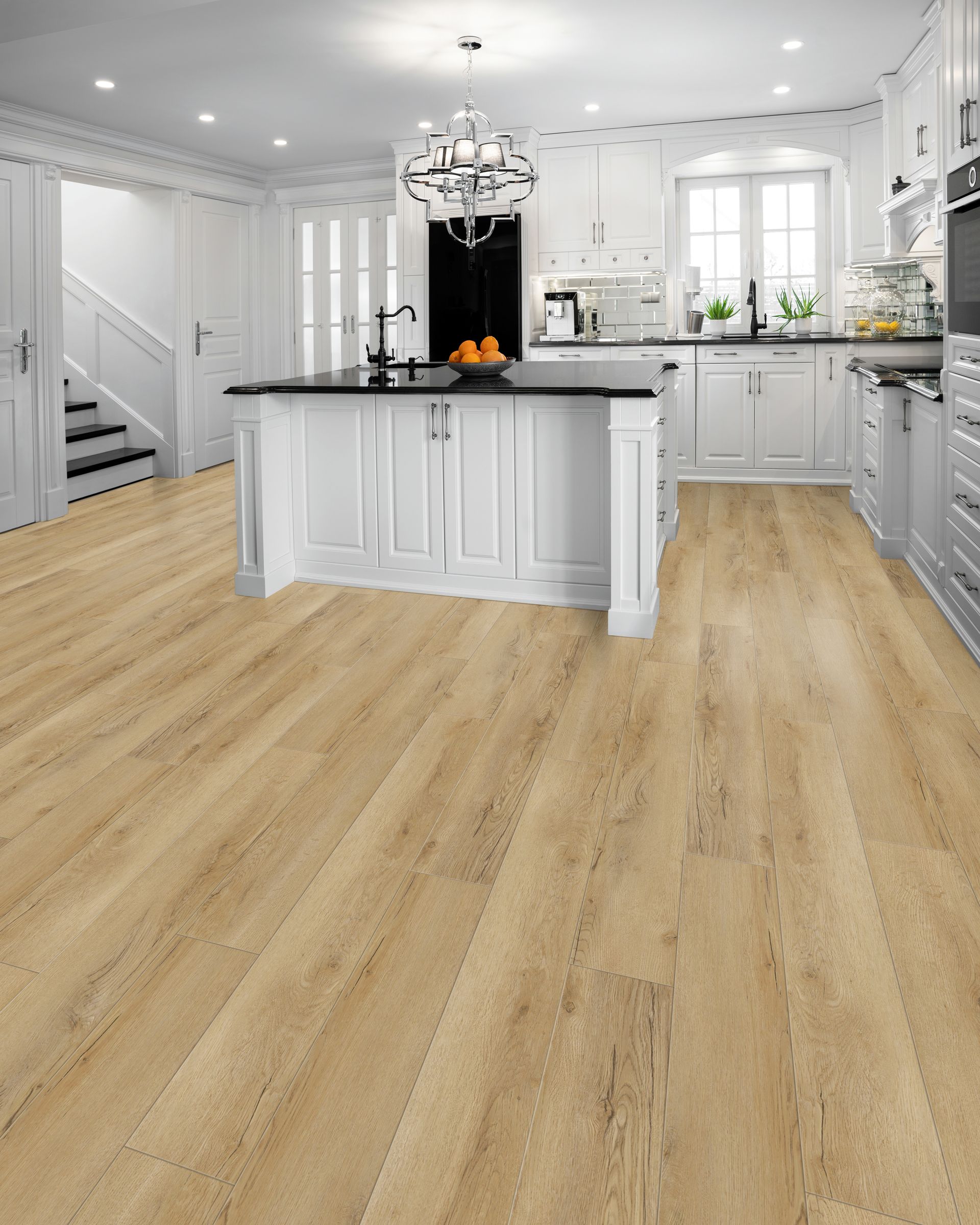 Bright modern kitchen with light wood flooring, white cabinets, and a black island chandelier