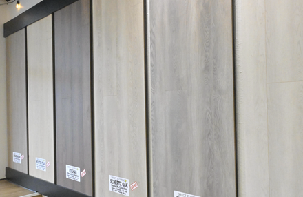 Row of large gray wall panels with small labels along the bottom in a showroom or store.