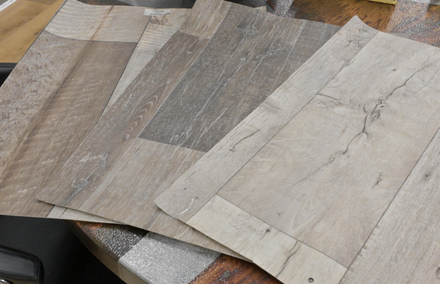 Assorted wood-look flooring samples in gray, beige, and brown tones laid out on a table