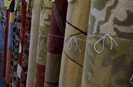 Patterned curtains in red, gold, and beige hanging on a display rack with white ties