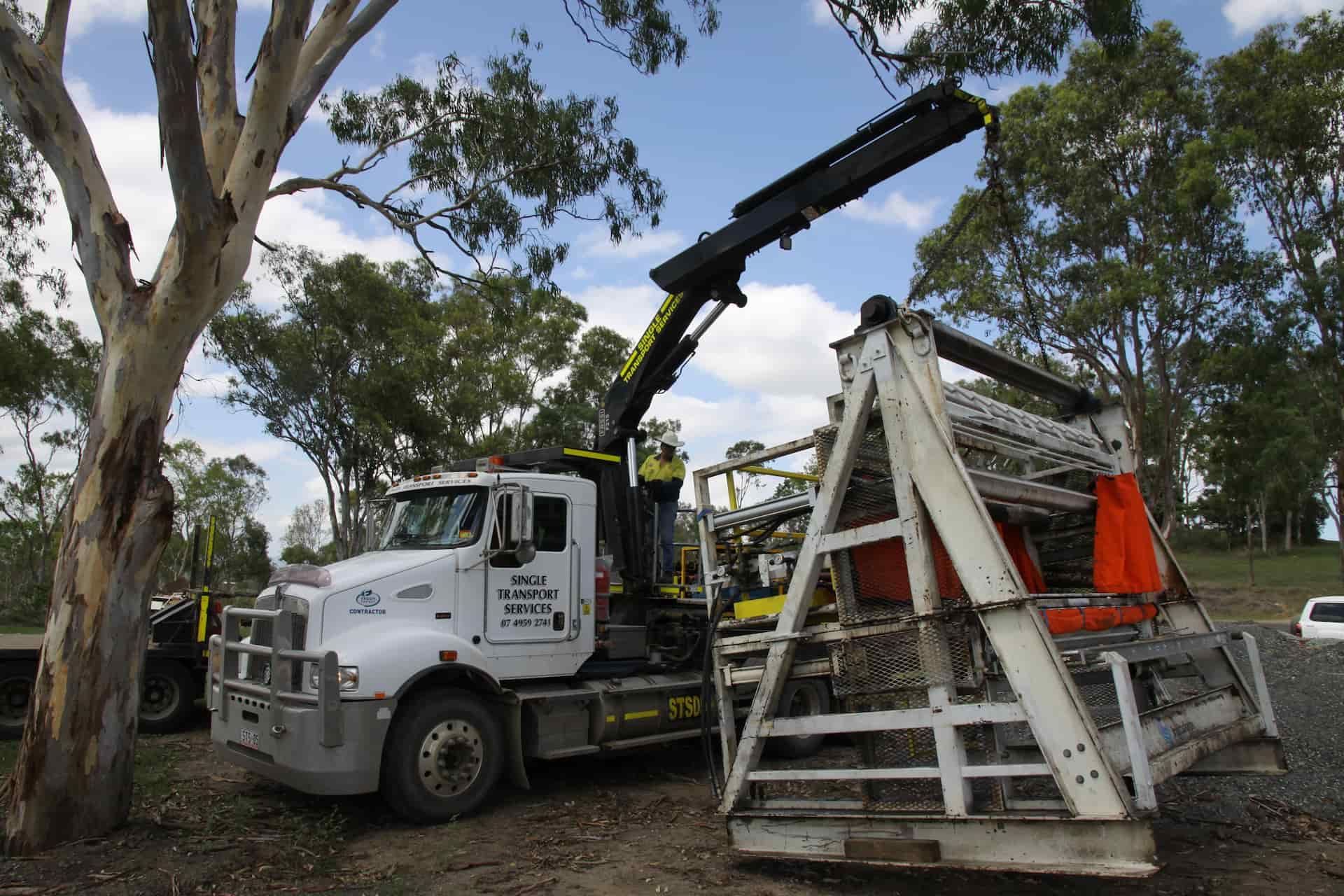 A Truck With A Crane Attached To It Is Parked Next To A Tree — Single Transport Services In Bowen, QLD