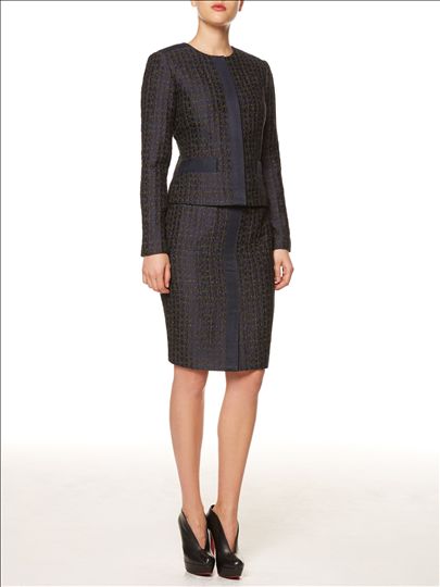 A woman is wearing a black suit and heels.