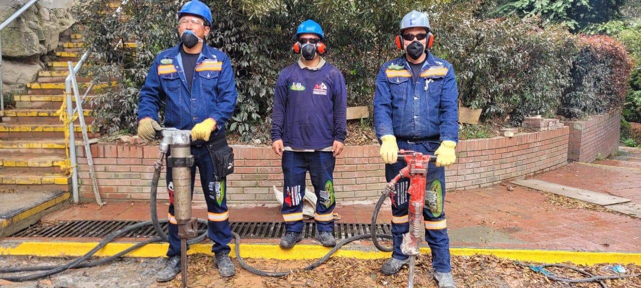 Tres trabajadores con uniformes azules y cascos de seguridad