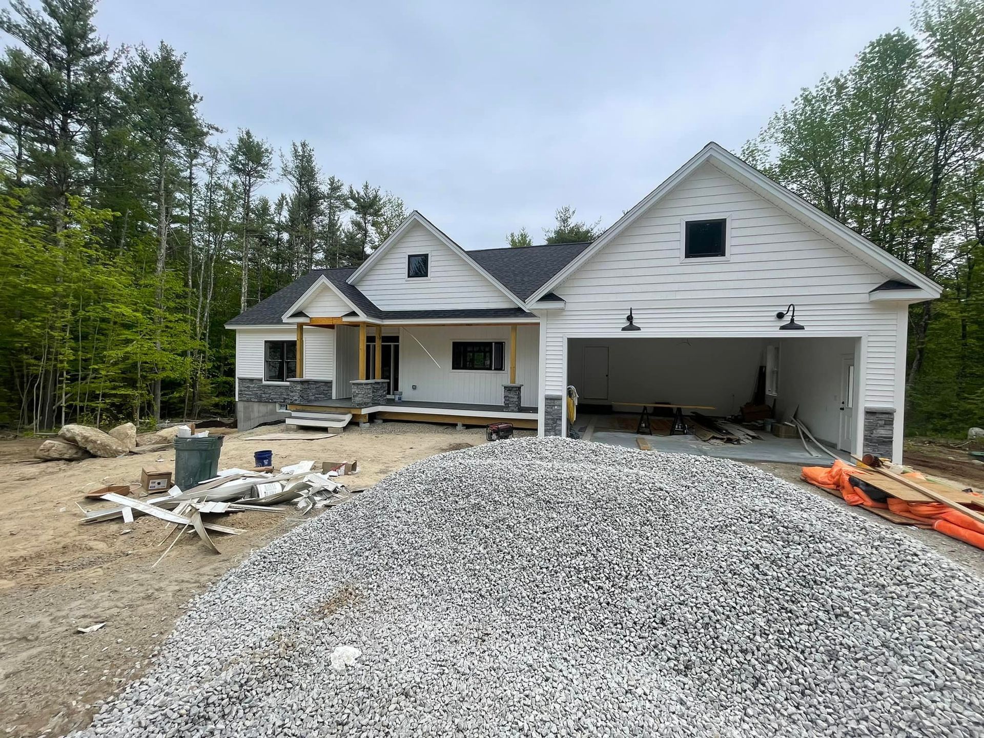 A white house is being built in the woods with a garage.