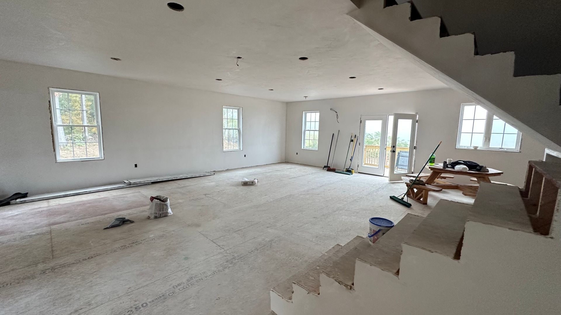 A large empty room with stairs and a lot of windows.