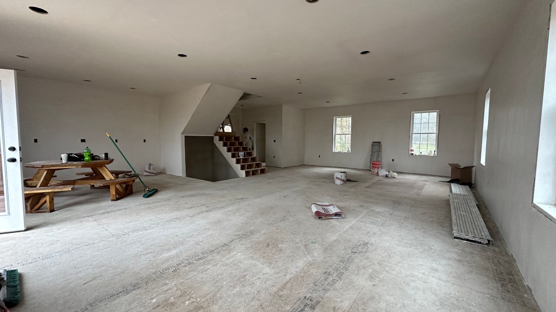 A large empty room with a picnic table and stairs.