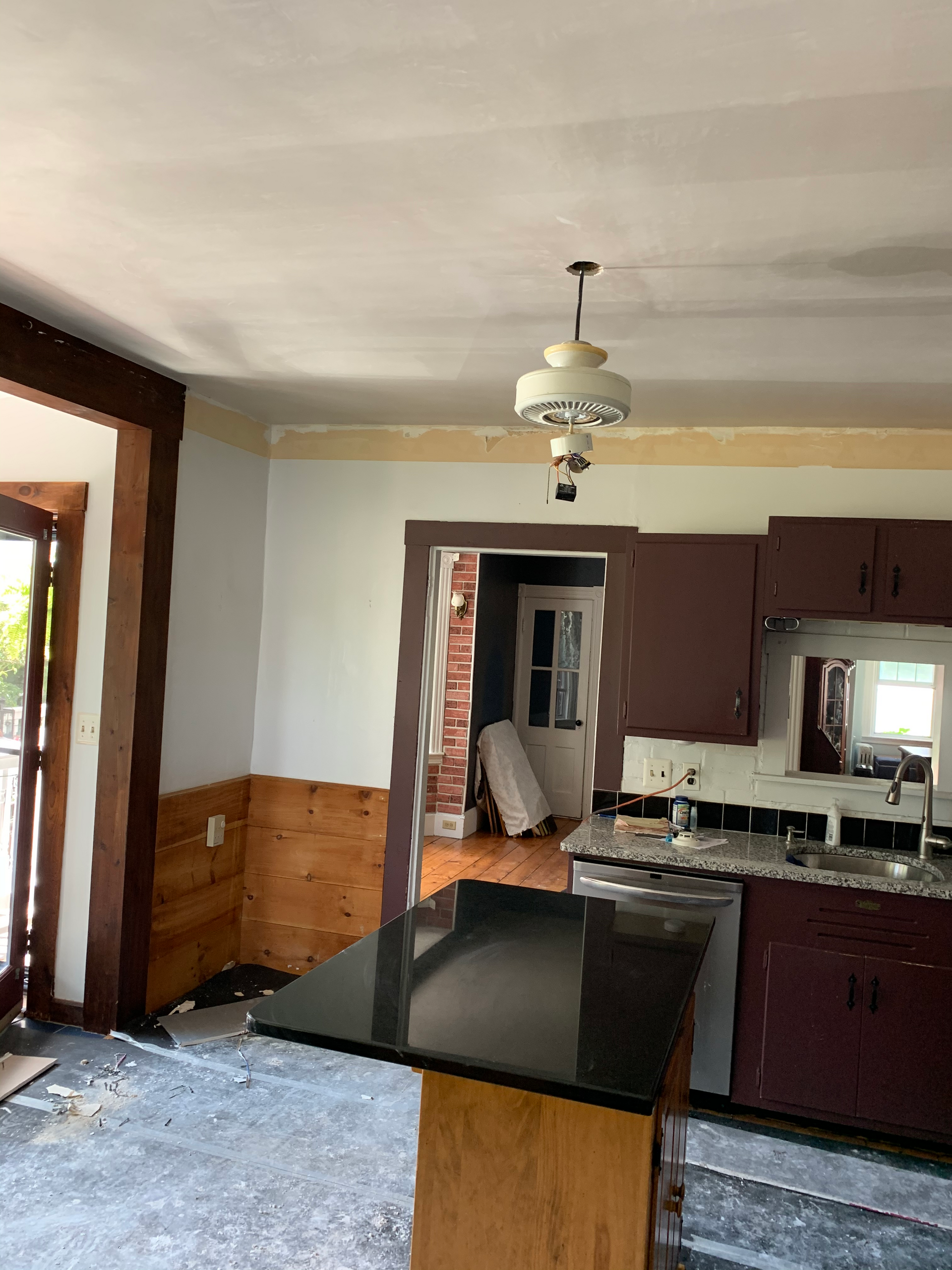 A kitchen with a black counter top and a ceiling fan.