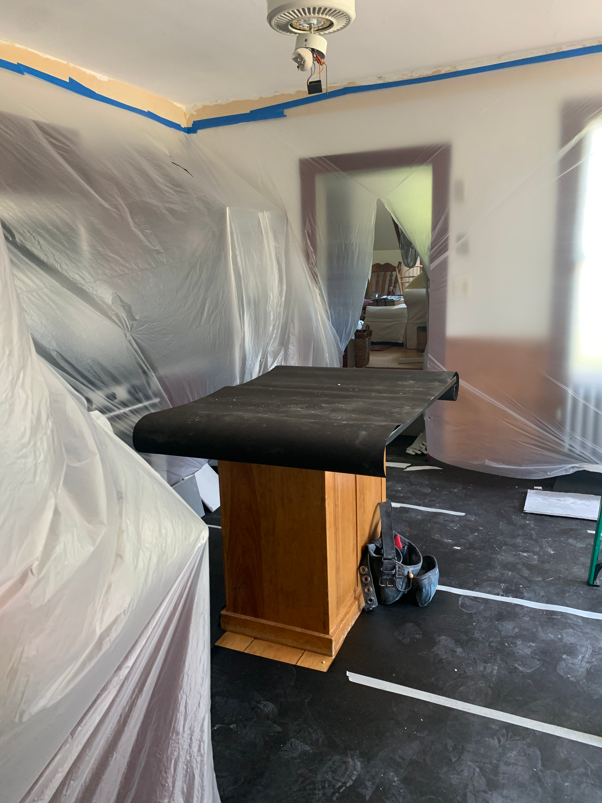A room with a table and a door covered in plastic.