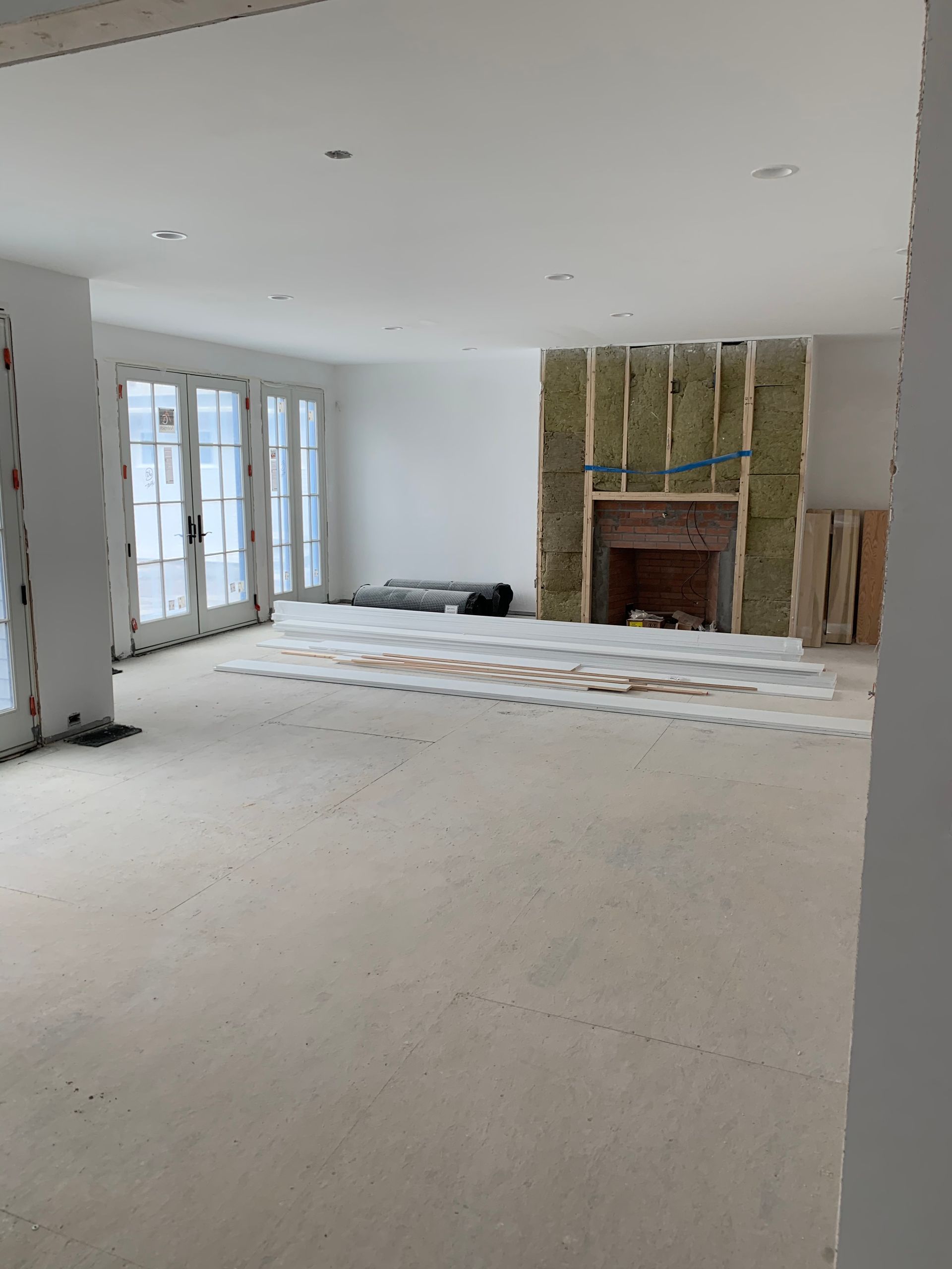 A large empty room with a fireplace and sliding glass doors.