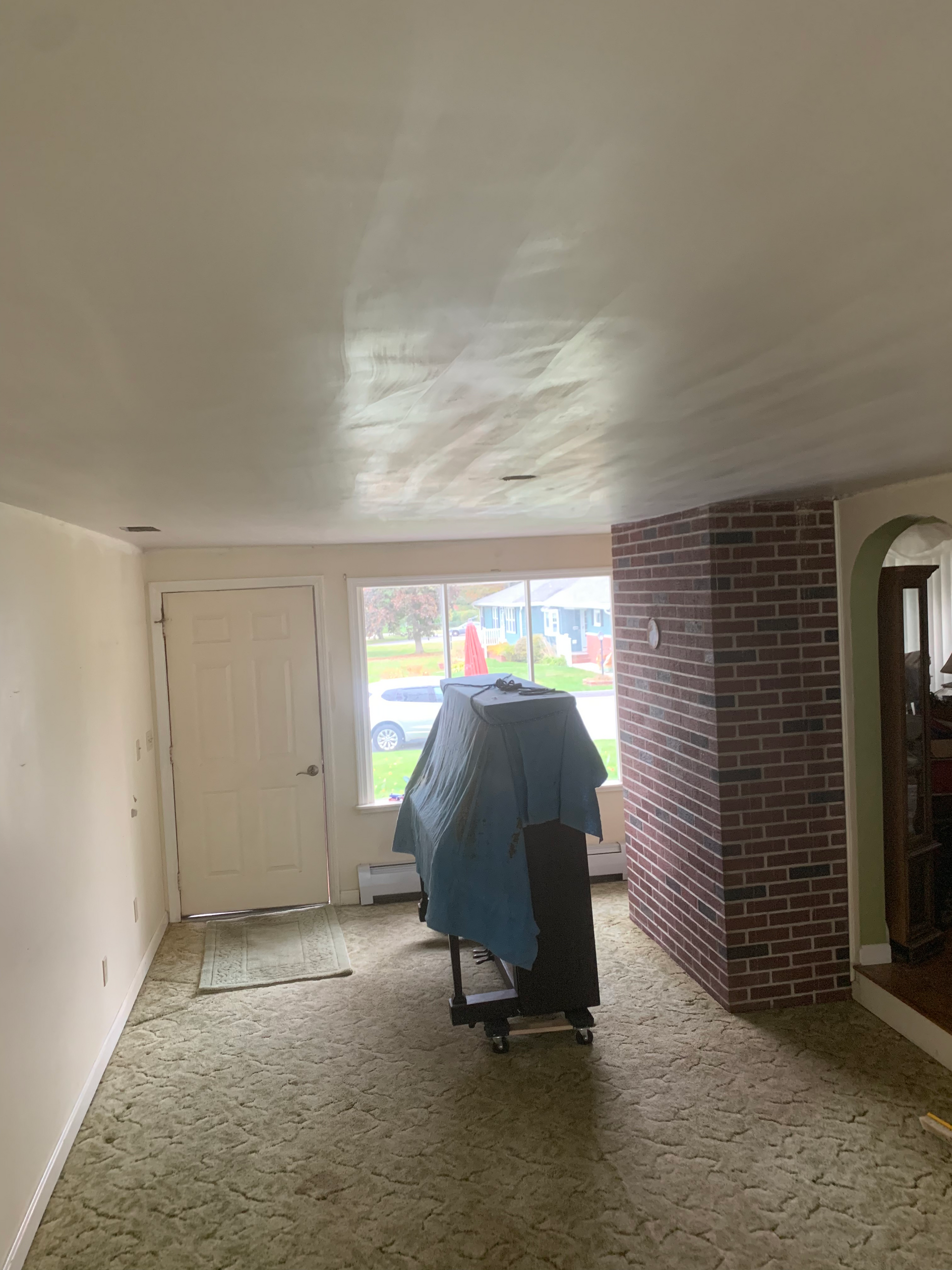 A living room with a piano and a brick wall.