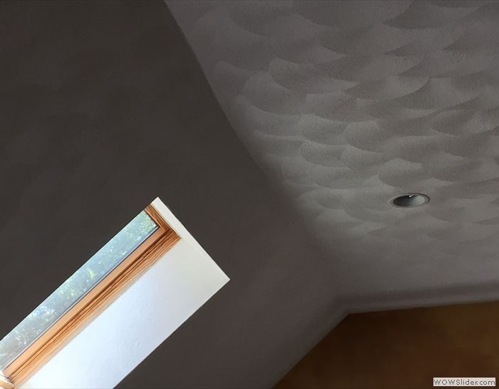 A room with a skylight and a ceiling that has a pattern on it