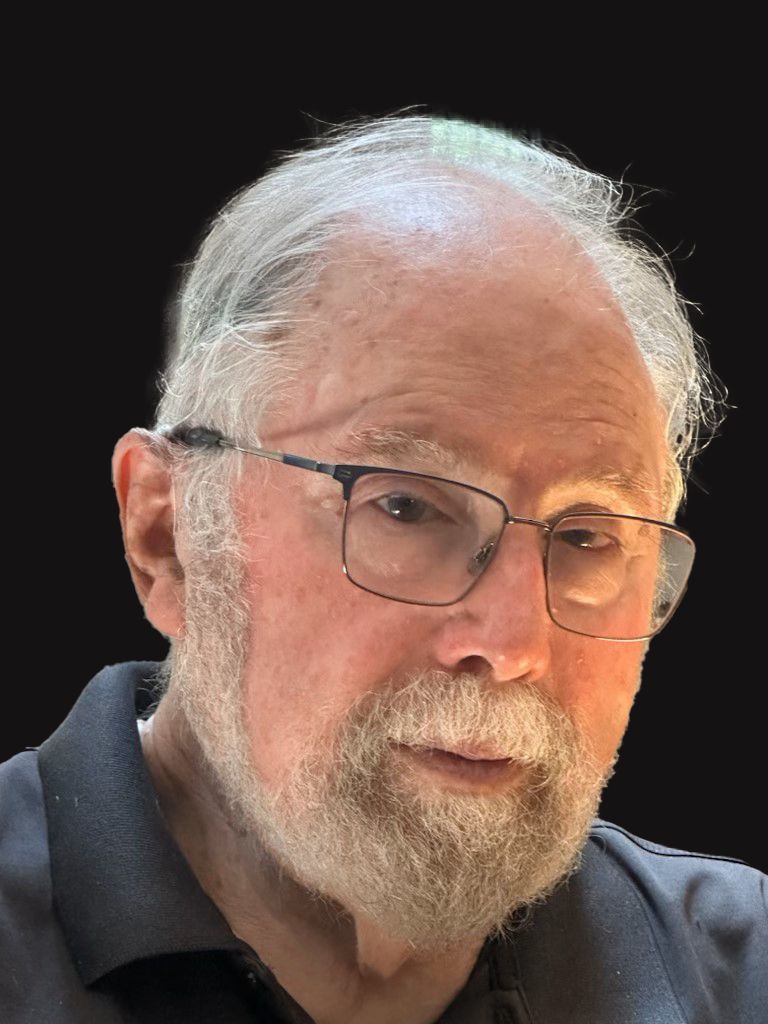 Elderly man with glasses and a beard, looking directly at the camera.
