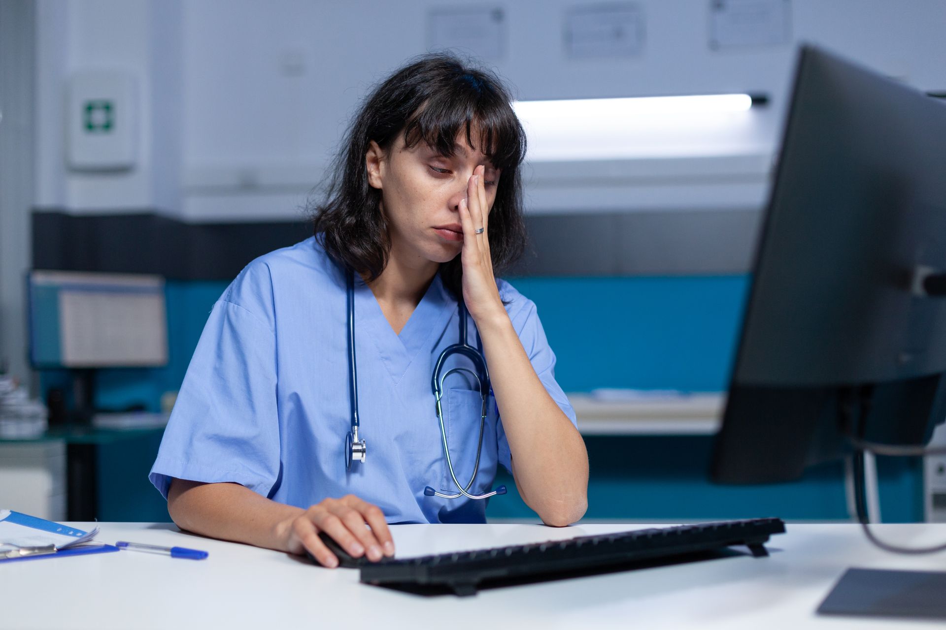 A healthcare worker struggles with an outdated software system, leading to frustration and fatigue.